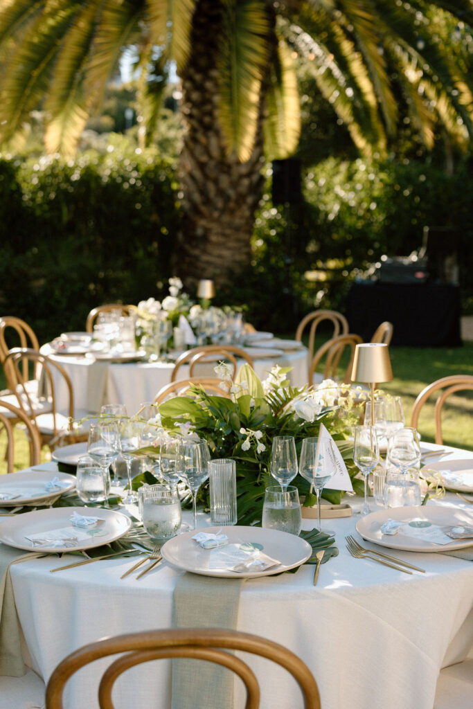 Outdoor wedding reception at Glen Cove Marina with serpentine head table, lush florals, and golden sunset light