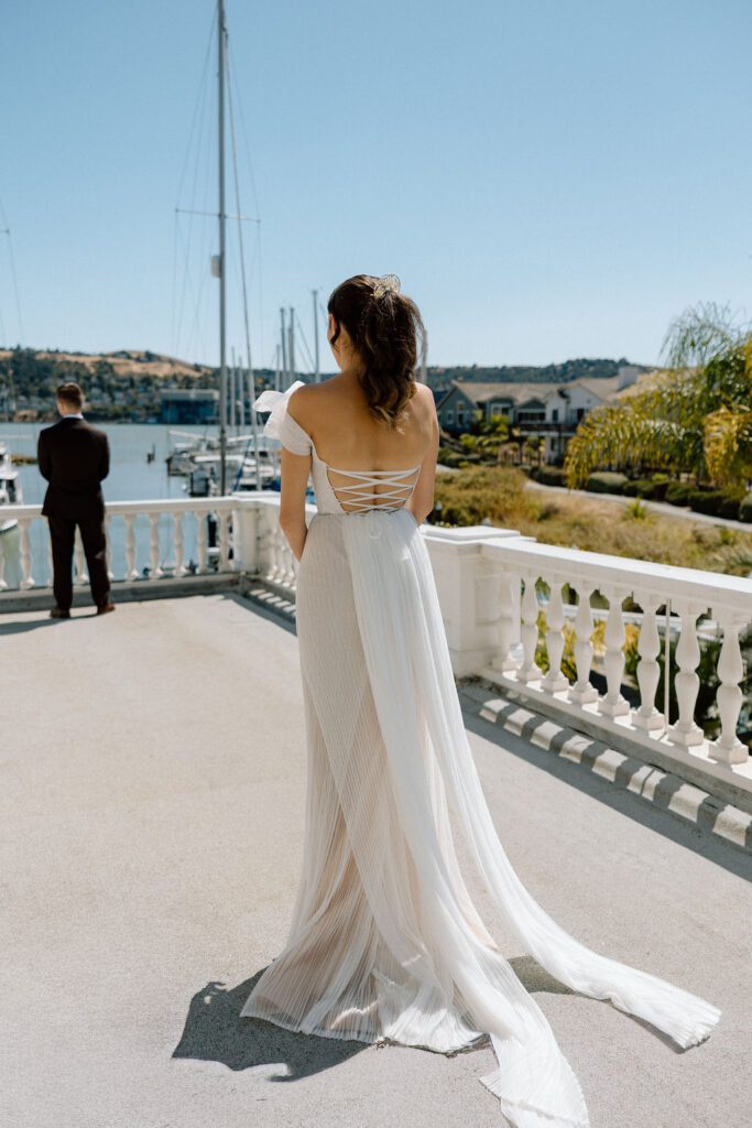 Bride and groom embracing during their first look on a marina balcony surrounded by sailboats