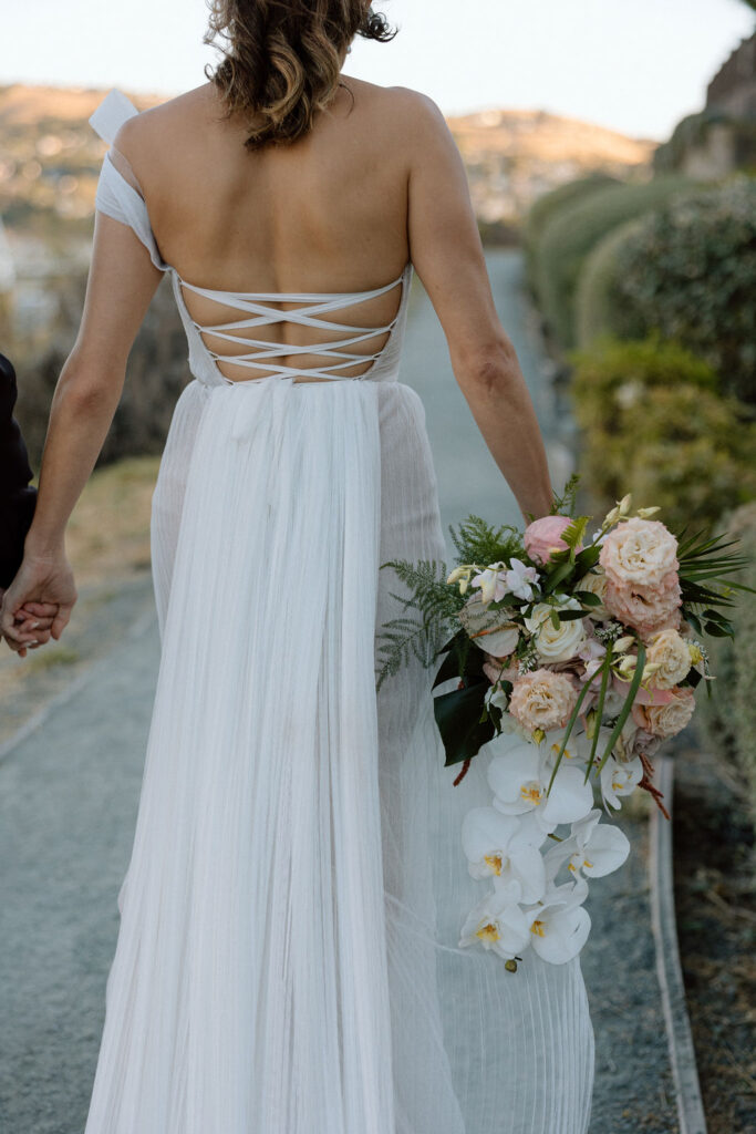 Bride and groom walking hand-in-hand near the water at sunset during their Glen Cove Marina wedding