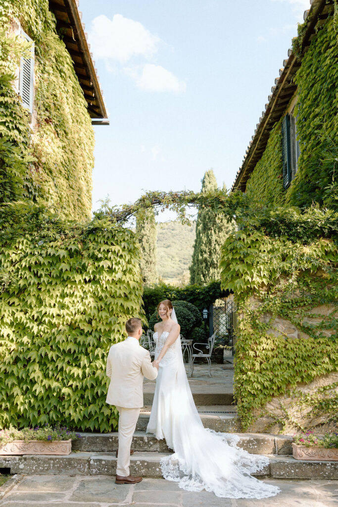 Bride and groom walking through the gardens of Villa di Piazzano in Tuscany, surrounded by cypress trees and rolling hills during an intimate destination wedding.
