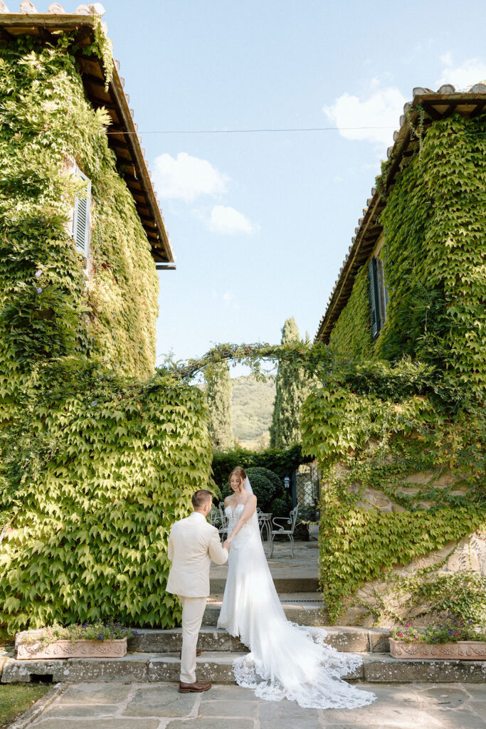 Bride and groom walking through the gardens of Villa di Piazzano in Tuscany, surrounded by cypress trees and rolling hills during an intimate destination wedding.