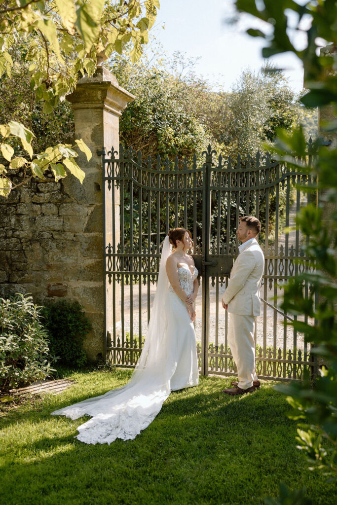 Bride and groom walking through the gardens of Villa di Piazzano in Tuscany, surrounded by cypress trees and rolling hills during an intimate destination wedding.