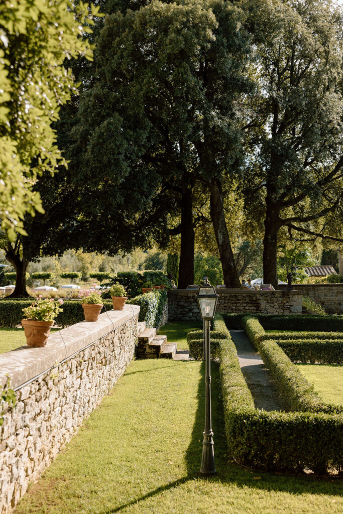 Bride and groom walking through the gardens of Villa di Piazzano in Tuscany, surrounded by cypress trees and rolling hills during an intimate destination wedding.