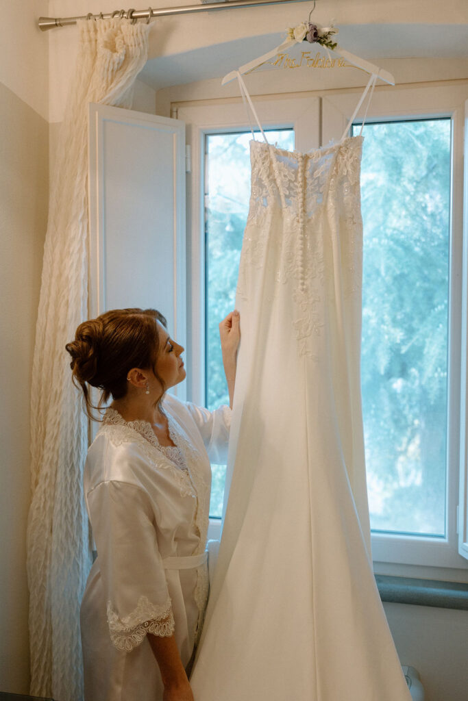Bride wearing a lace wedding gown with corseted bodice and cathedral veil while getting ready in an antique-filled suite at Villa di Piazzano.