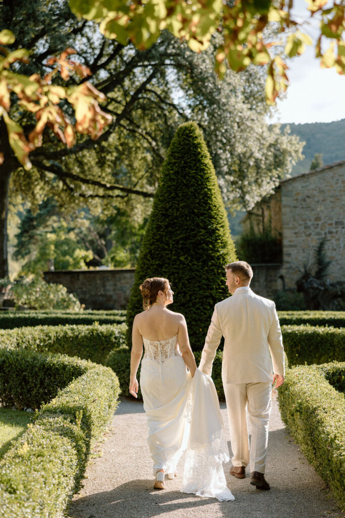 Bride and groom walking through the gardens of Villa di Piazzano in Tuscany, surrounded by cypress trees and rolling hills during an intimate destination wedding.