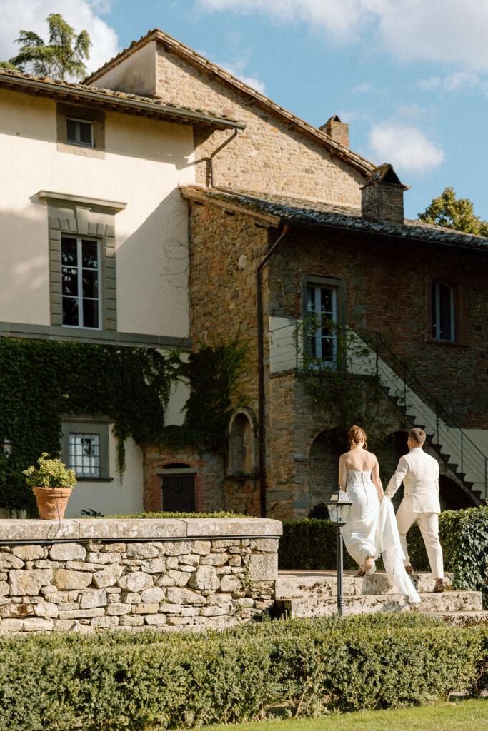 Bride and groom walking through the gardens of Villa di Piazzano in Tuscany, surrounded by cypress trees and rolling hills during an intimate destination wedding.