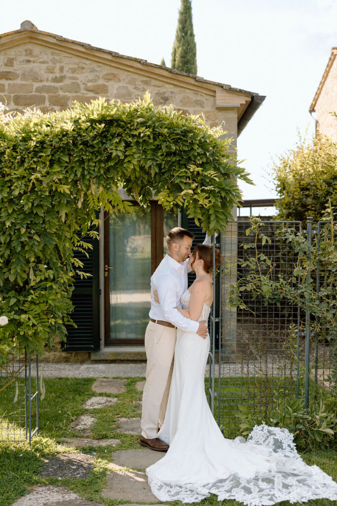 Bride and groom walking through the gardens of Villa di Piazzano in Tuscany, surrounded by cypress trees and rolling hills during an intimate destination wedding.