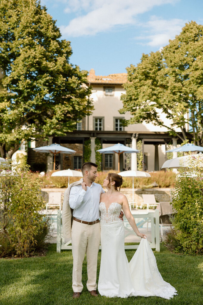 Bride and groom walking through the gardens of Villa di Piazzano in Tuscany, surrounded by cypress trees and rolling hills during an intimate destination wedding.