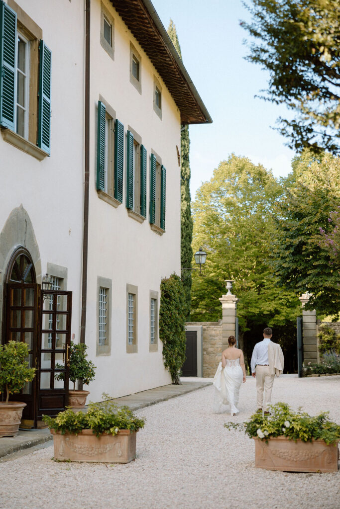 Bride and groom walking through the gardens of Villa di Piazzano in Tuscany, surrounded by cypress trees and rolling hills during an intimate destination wedding.