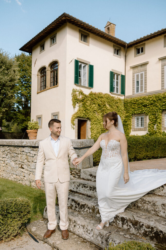 Bride and groom walking through the gardens of Villa di Piazzano in Tuscany, surrounded by cypress trees and rolling hills during an intimate destination wedding.
