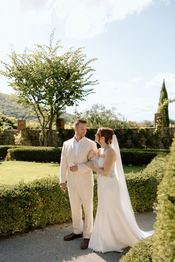 Bride and groom walking through the gardens of Villa di Piazzano in Tuscany, surrounded by cypress trees and rolling hills during an intimate destination wedding.