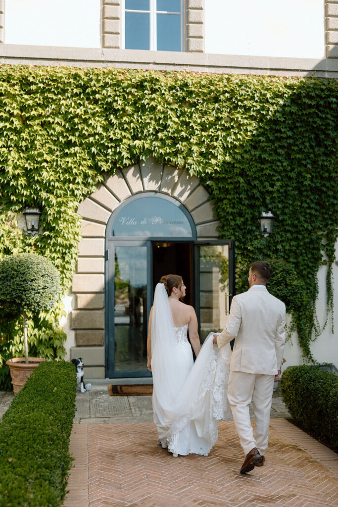 Bride and groom walking through the gardens of Villa di Piazzano in Tuscany, surrounded by cypress trees and rolling hills during an intimate destination wedding.