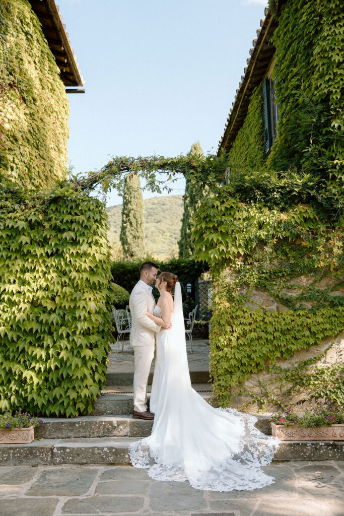 Bride and groom walking through the gardens of Villa di Piazzano in Tuscany, surrounded by cypress trees and rolling hills during an intimate destination wedding.