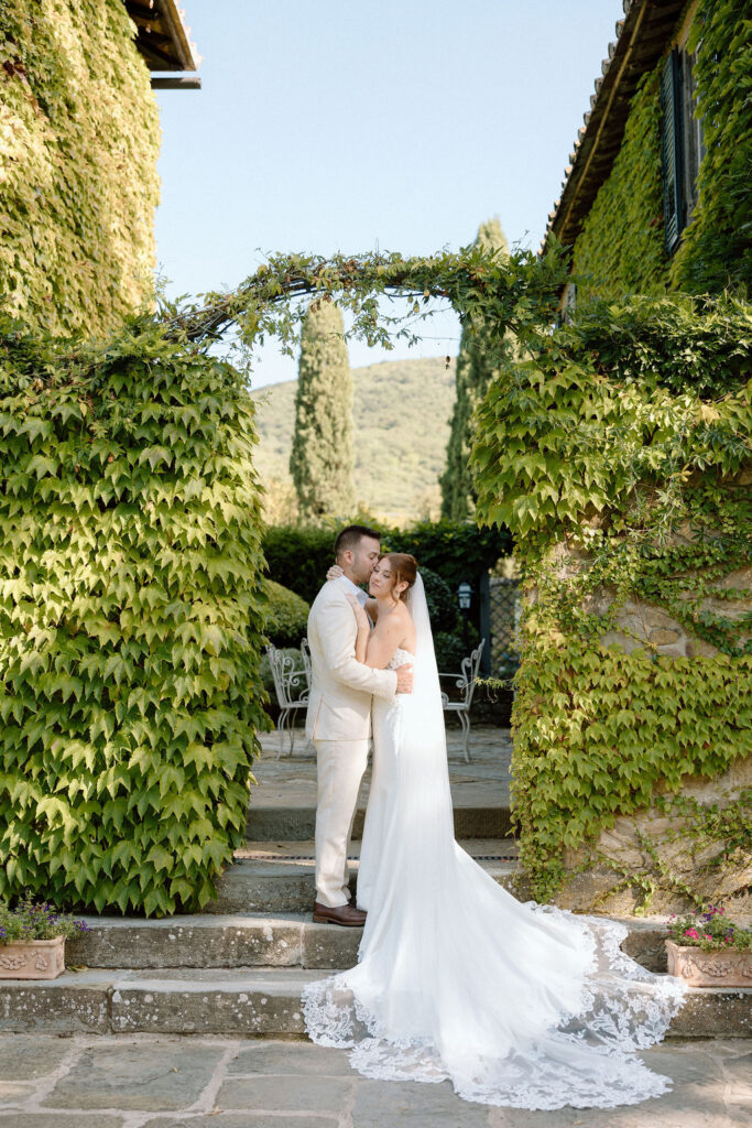 Bride and groom walking through the gardens of Villa di Piazzano in Tuscany, surrounded by cypress trees and rolling hills during an intimate destination wedding.