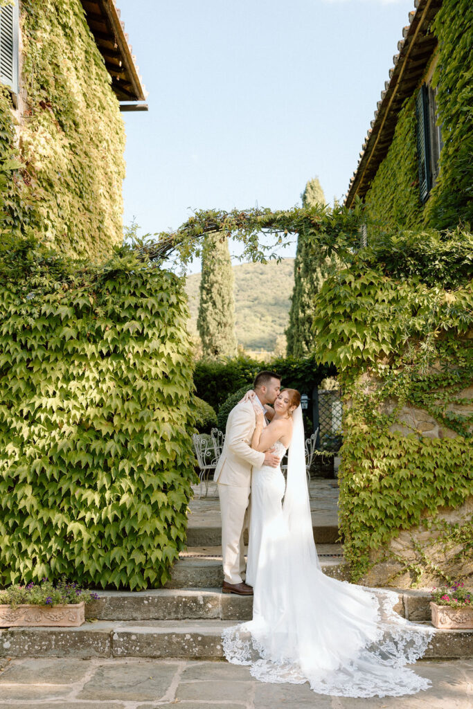 Bride and groom walking through the gardens of Villa di Piazzano in Tuscany, surrounded by cypress trees and rolling hills during an intimate destination wedding.