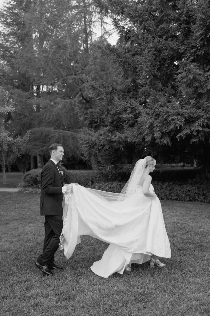 Groom holding brides dress as they walking casually through venue captured candidly by california wedding photographer 
