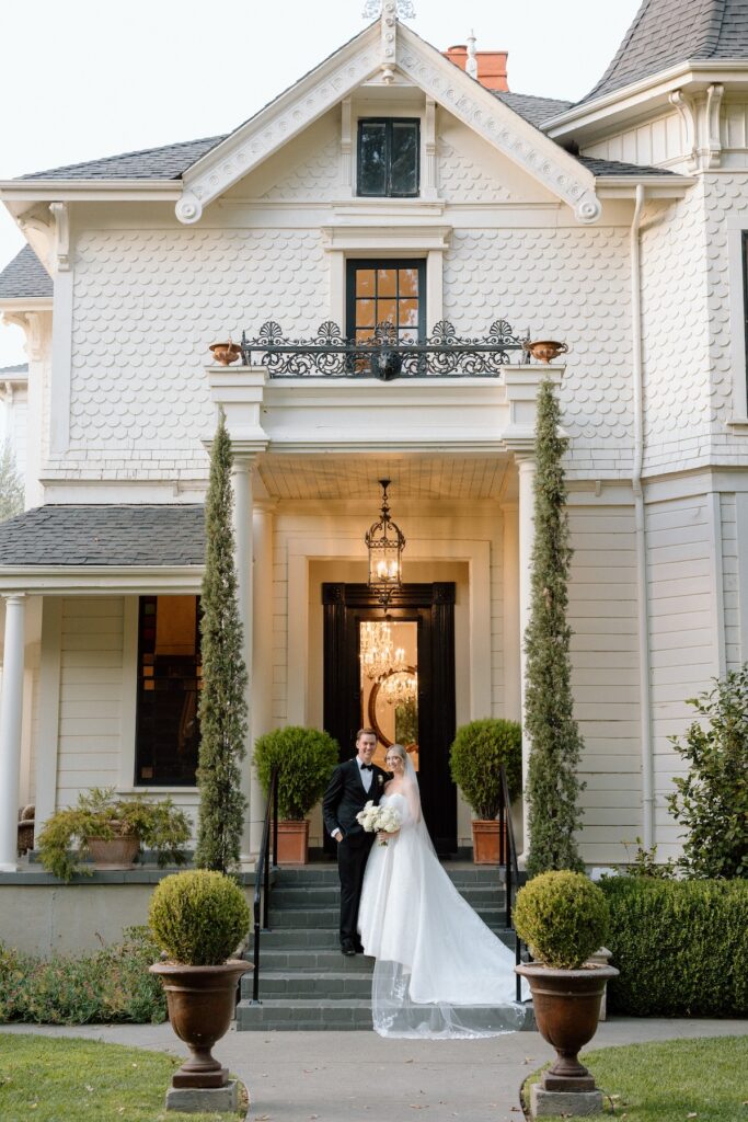 Bride and groom posing in front of Park Winters old victorian house 