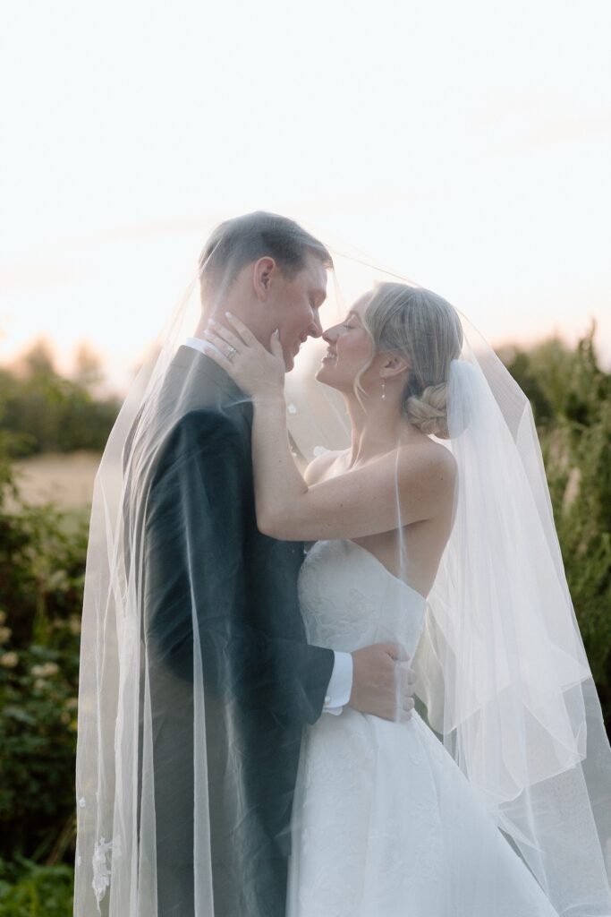 bride and groom pose romantically under the brides veil during sunset on wedding day at california wedding 