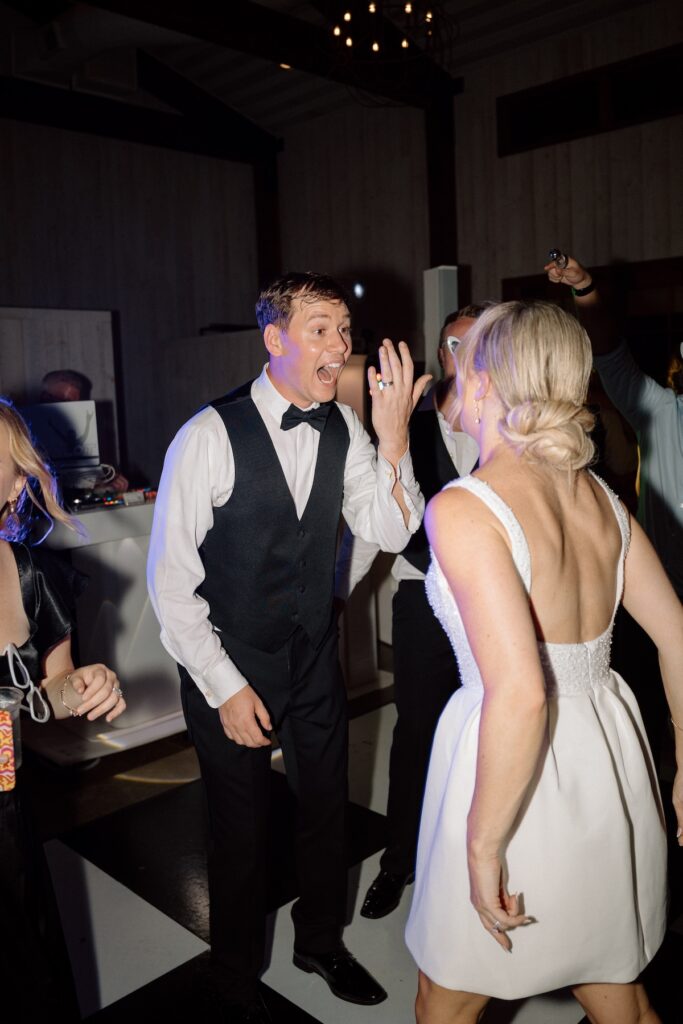 Bride and groom excitedly show off their wedding rings to each other while dancing wedding reception party