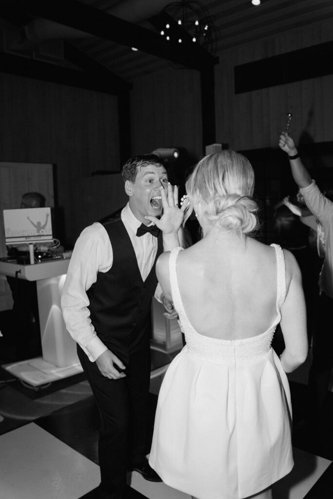 Bride and groom excitedly show off their wedding rings to each other while dancing wedding reception party