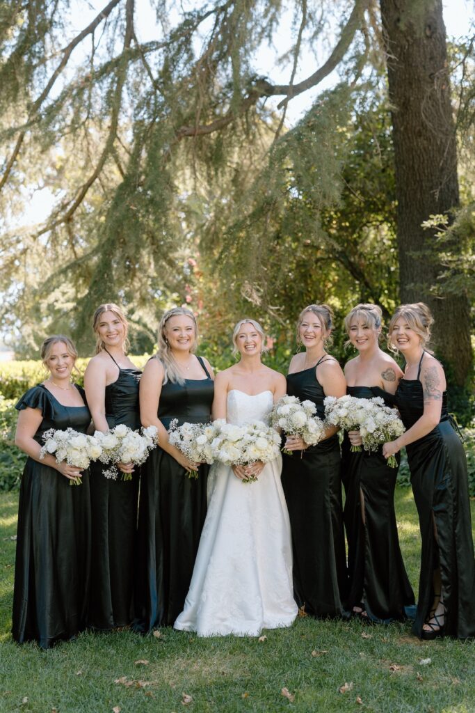 Bride poses with bridesmaids in black dresses on wedding day at Park Winters