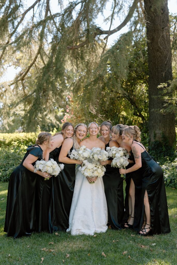 Bride poses with bridesmaids in black dresses on wedding day at Park Winters