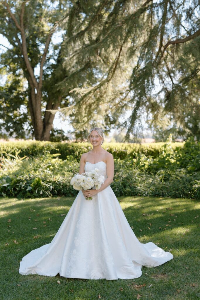 Beautiful bride poses with timeless white floral bouquet in the garden at Park Winters
