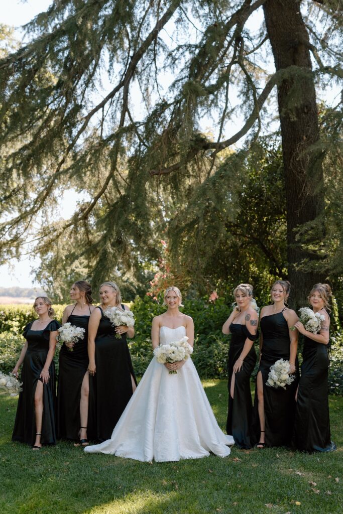 Bride poses with bridesmaids in black dresses on wedding day at Park Winters