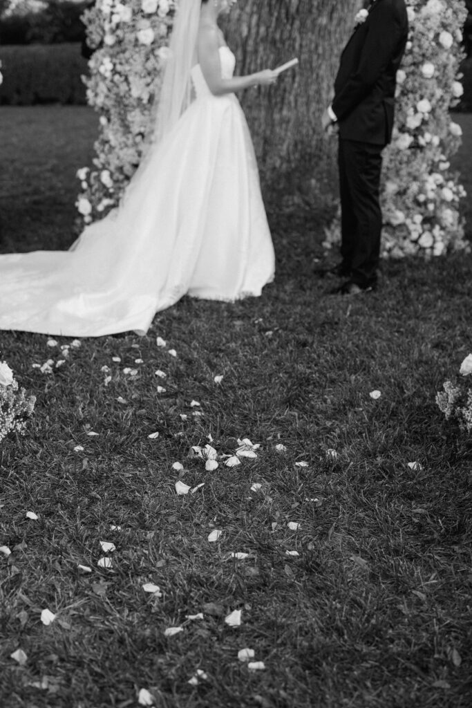 bride and groom share vows with floral arch behind them captured by california wedding photographer