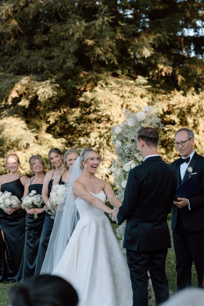 bride and groom share vows with floral arch behind them captured by california wedding photographer