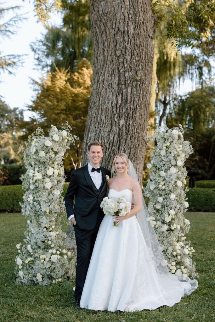 pose with floral arch behind them captured by california wedding photographer