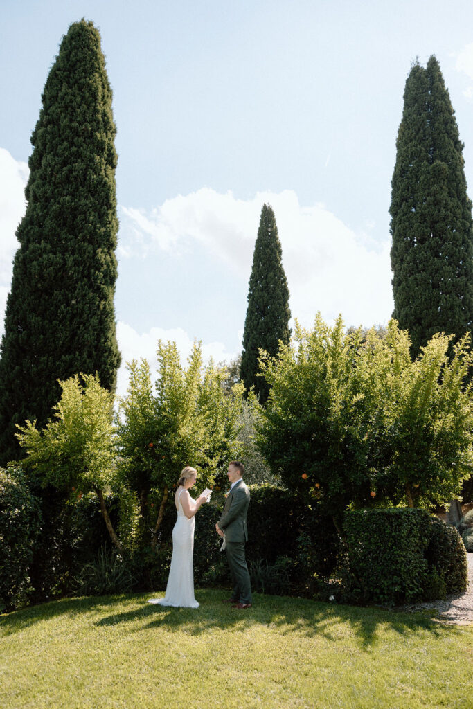 Bride and groom standing together during their private elopement ceremony in Tuscany, framed by soft light and the Italian landscape.