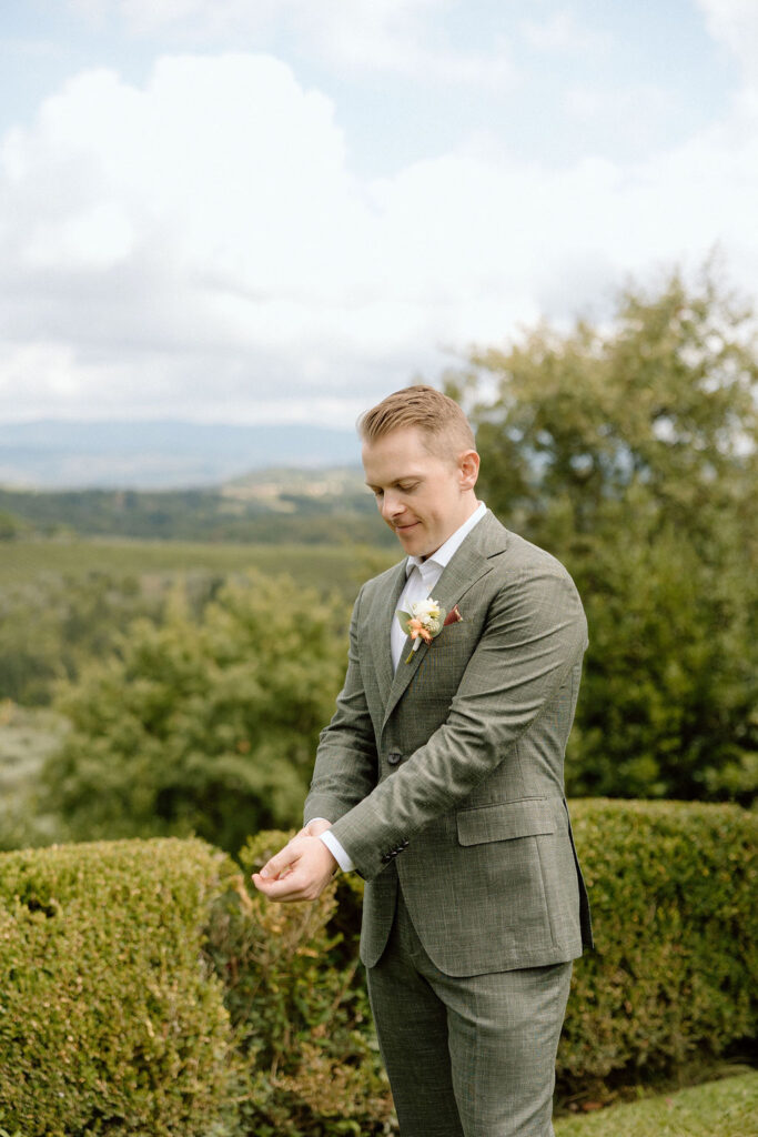 Groom preparing for an intimate Italian destination wedding, adjusting his suit in soft natural light.
