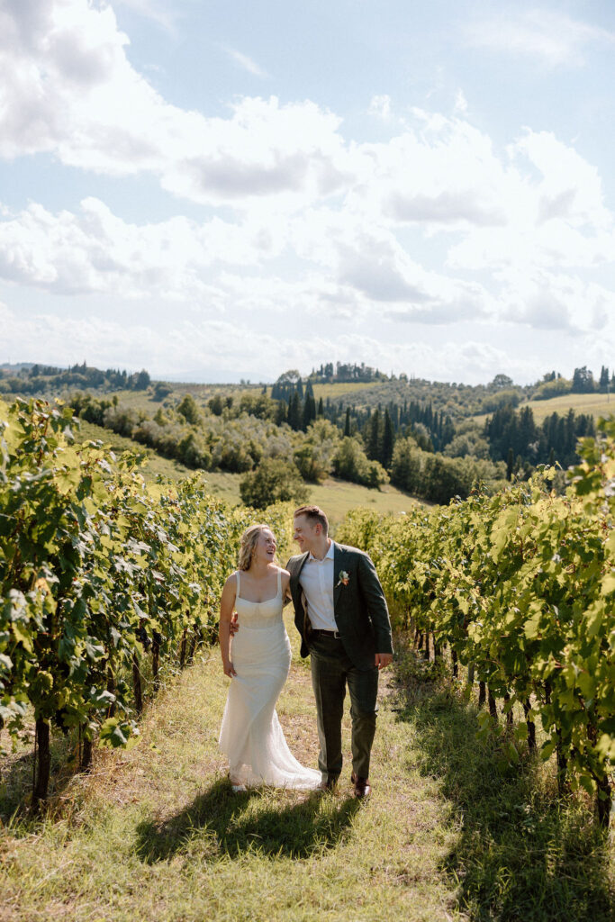 Couple strolling through rolling vineyard rows in the Tuscan countryside, captured in soft light during a destination elopement in Italy.