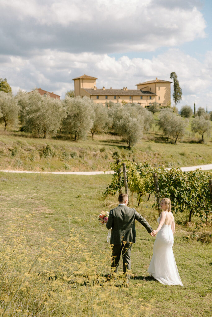 Bride and groom walking through garden paths of the historic villa after their elopement with stone architecture and olive trees.