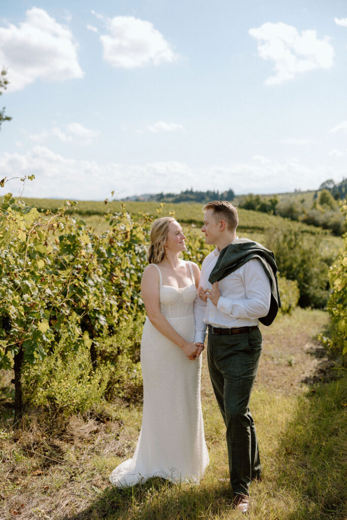 Couple walking through vineyard rows in Tuscany, sharing a quiet moment during their destination wedding in Italy.