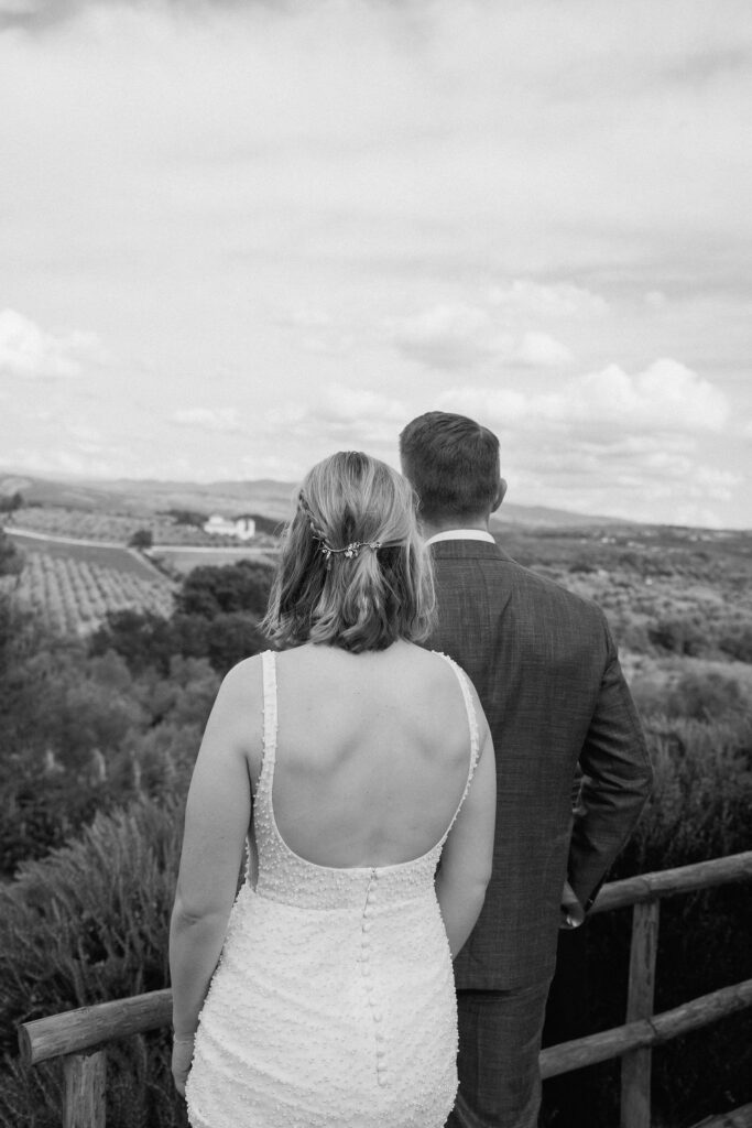 Scenic portrait of the couple overlooking the Tuscan countryside at COMO Castello Del Nero, celebrating their elopement in Italy.