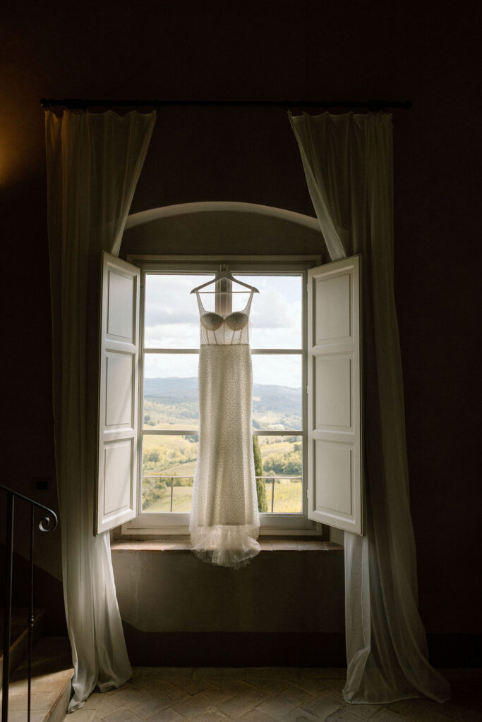 Bride getting ready for her Tuscan elopement, wearing a lace wedding gown in soft natural light inside a countryside villa.