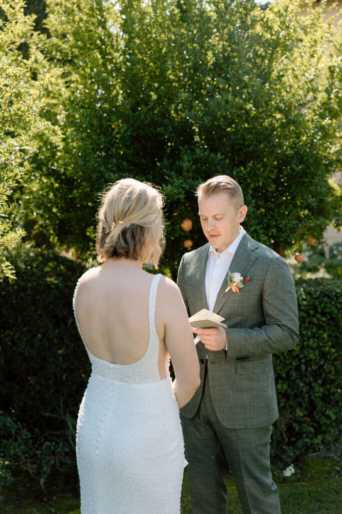 Intimate Tuscan elopement ceremony with the bride and groom exchanging vows surrounded by rolling hills and countryside views in Italy.
