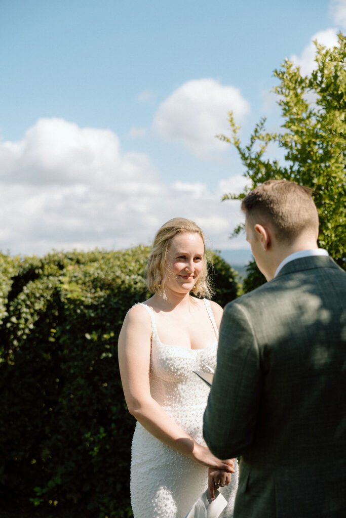 Couple exchanging vows during an intimate Italian elopement ceremony set against the rolling hills of Tuscany.