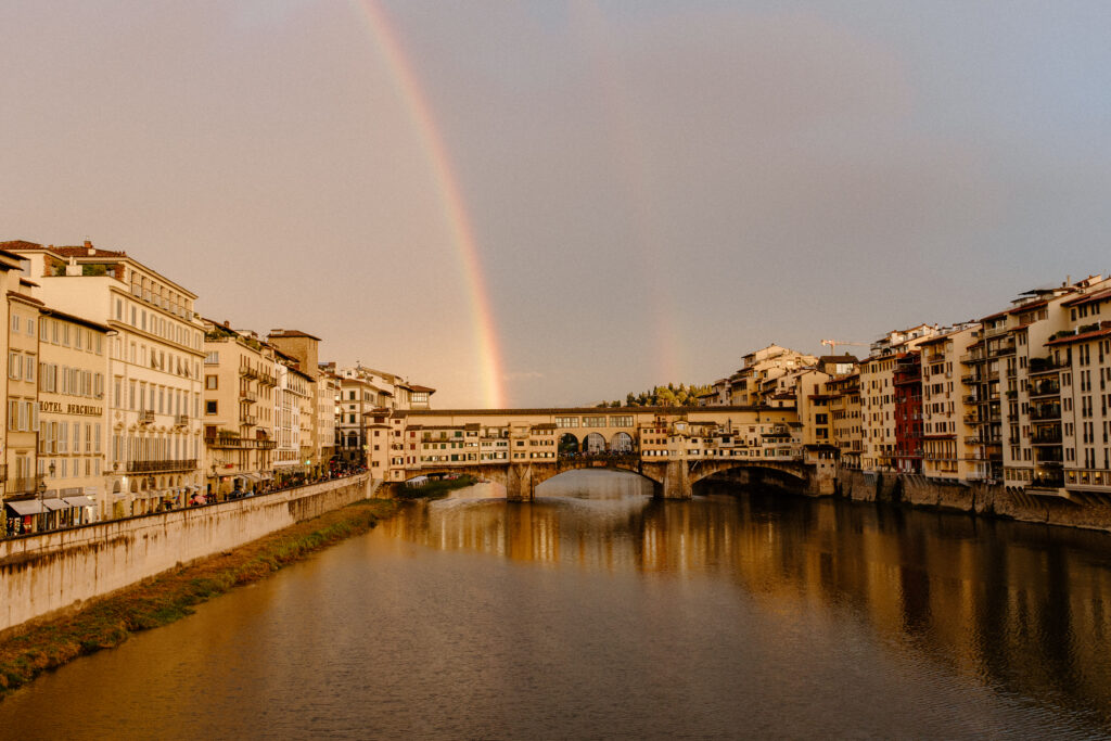 The ponte vecchio in florence italy with a double rainbow overhead taken by destination wedding photographer katelyn bradley photography