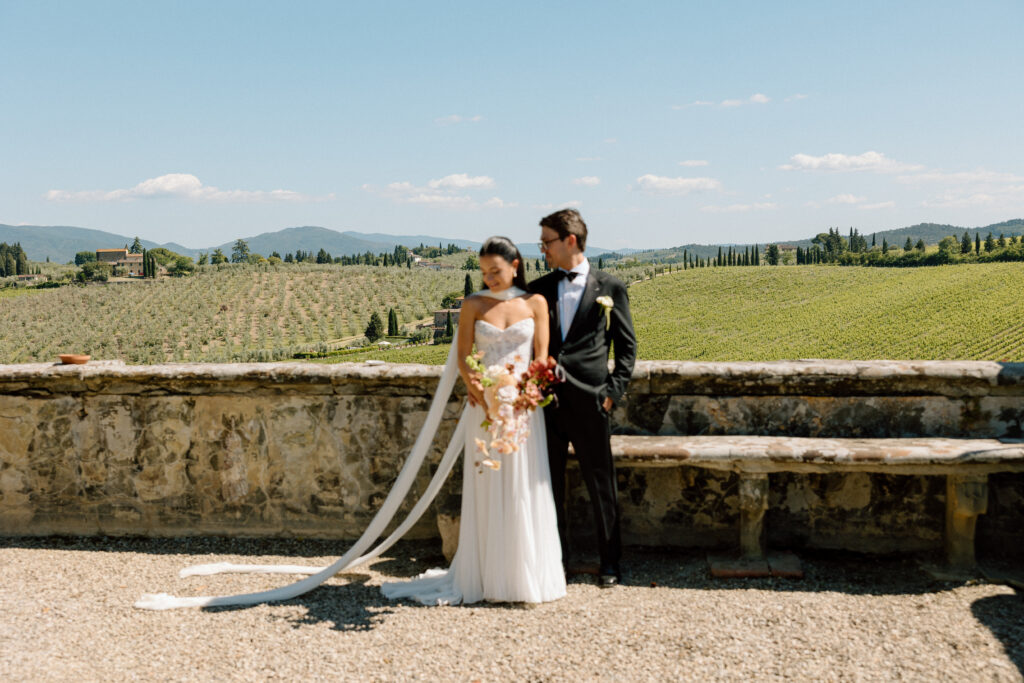 With the Tuscan rolling hills in the background, bride and groom pose for a photo on their wedding day at Villa Corsini jsut a few miles outside of Florence, Italy